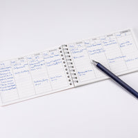 Small notepad with handwritten notes on a white surface with a pen next to it.